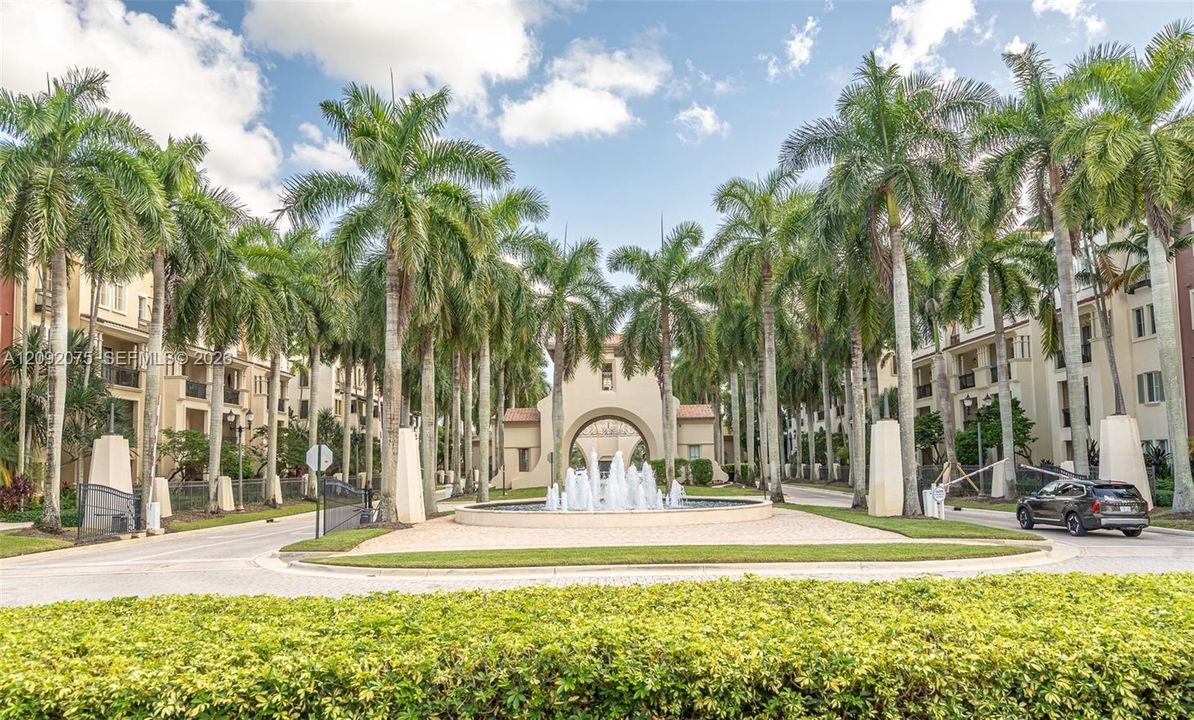Grand entry featuring a central fountain, lush landscaping, and mature palm trees