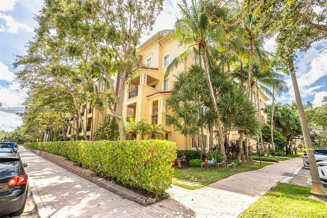 Multi-story residential structure with a stucco exterior, multiple private balconies, and a tile roof