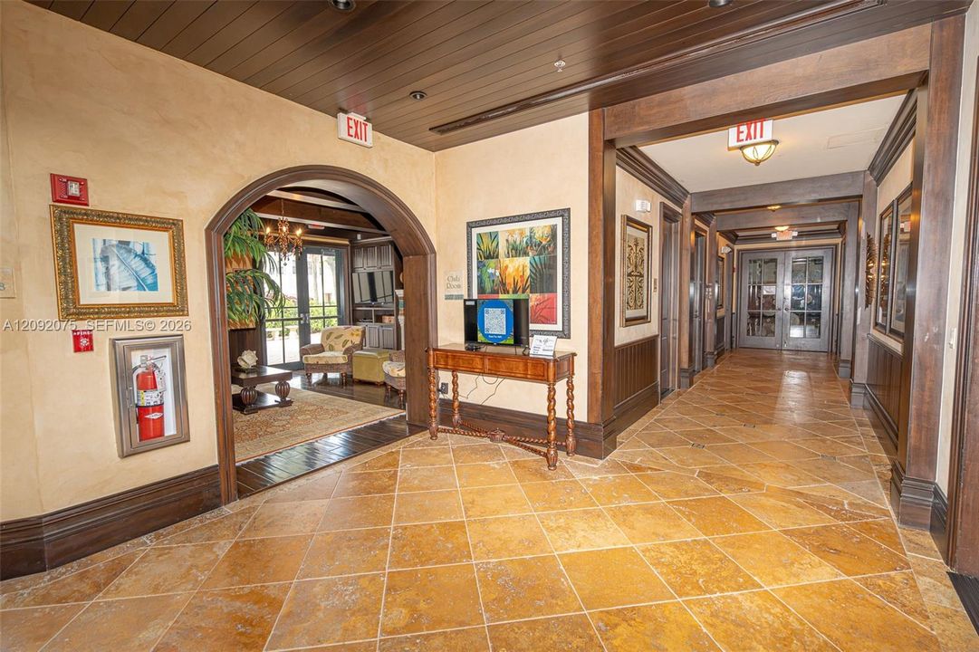 Tiled flooring, dark wood trim, wood paneled ceiling, arched entryway, and double glass doors