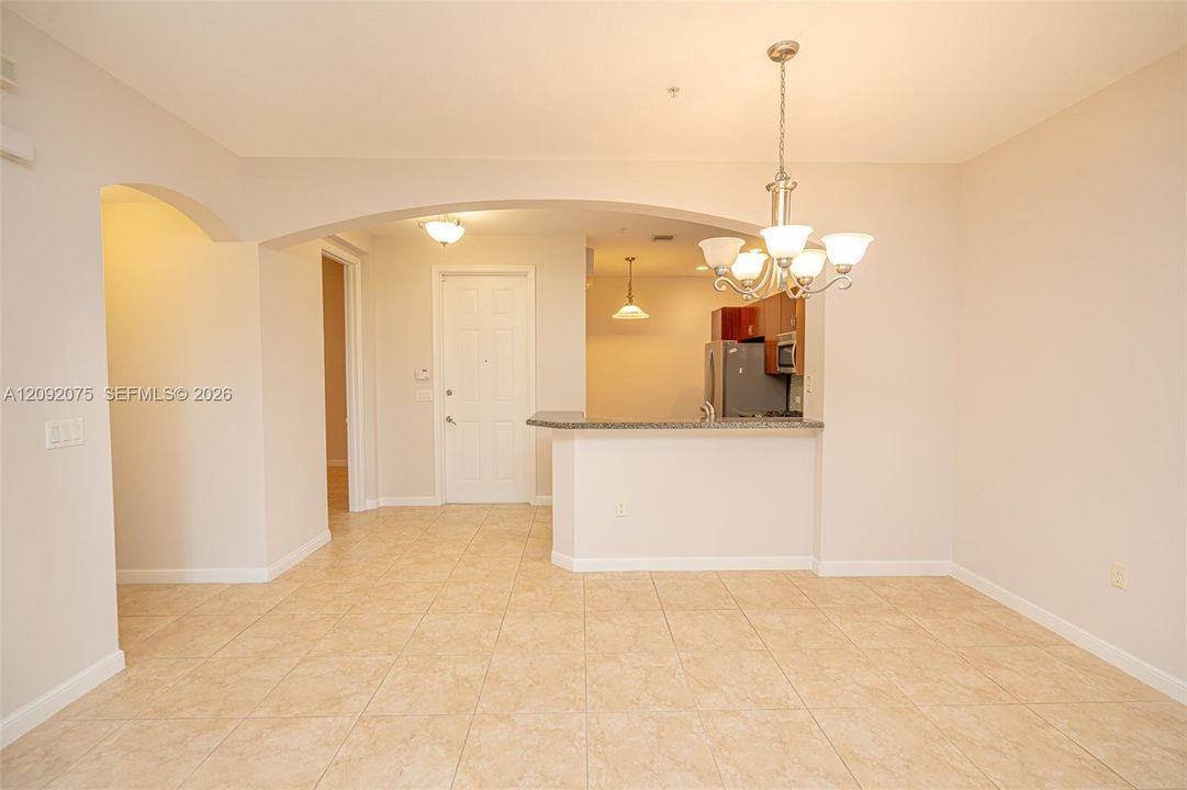 Tile flooring, overhead chandelier, arched doorways, breakfast bar, and stainless-steel appliances