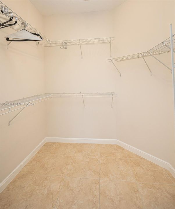 Spacious walk-in closet featuring wire shelving, wire hanging rods, and tile flooring