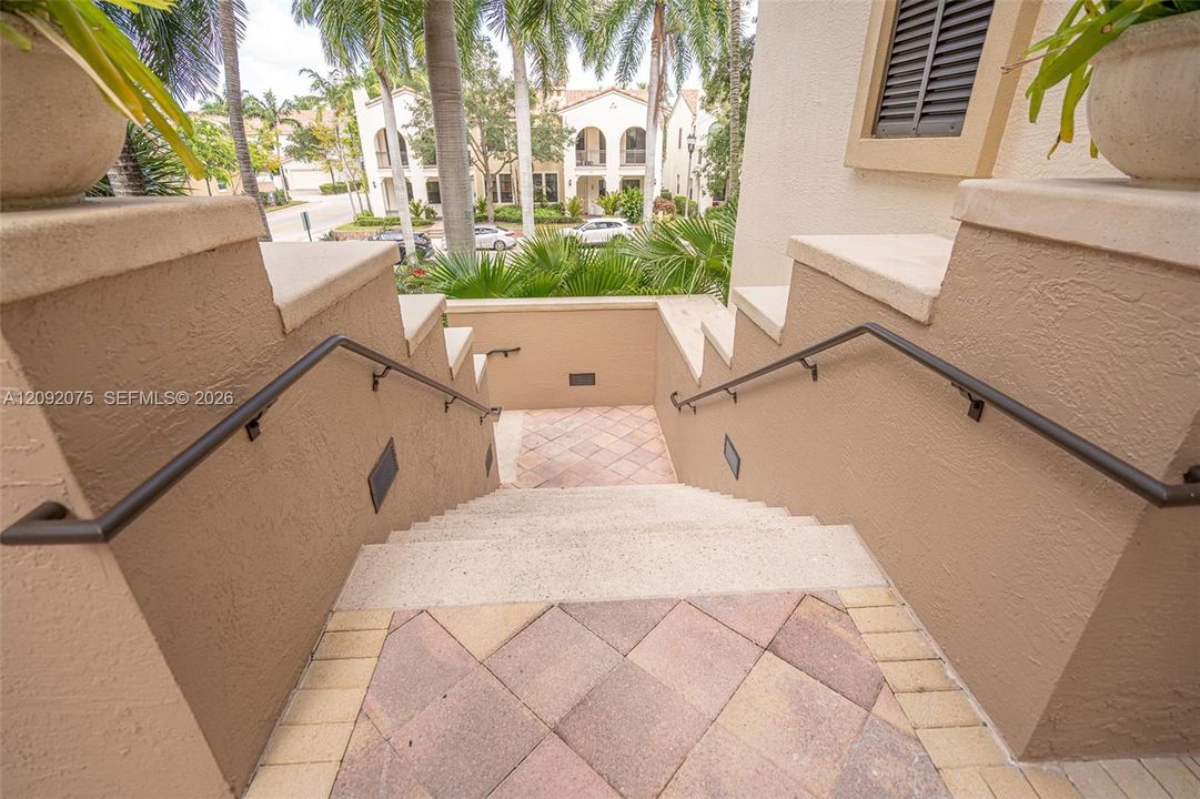 Exterior staircase with stucco walls, integrated wall lighting, and wrought iron handrails
