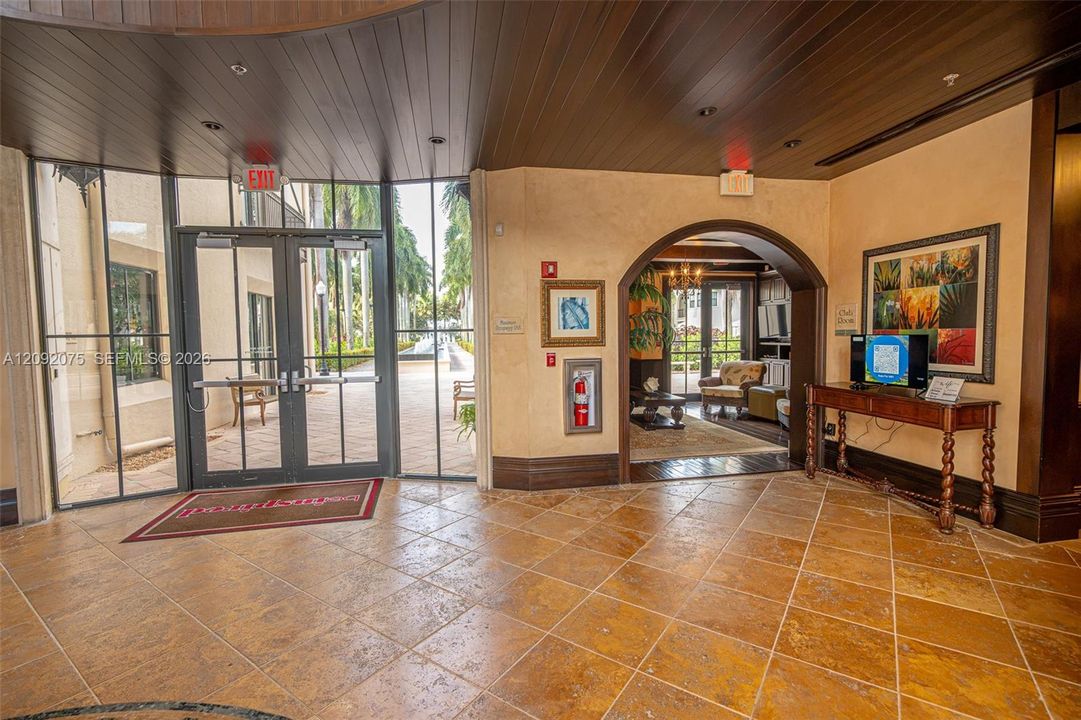 Tiled flooring with an arched entry, dark wood-paneled ceiling, and glass double doors