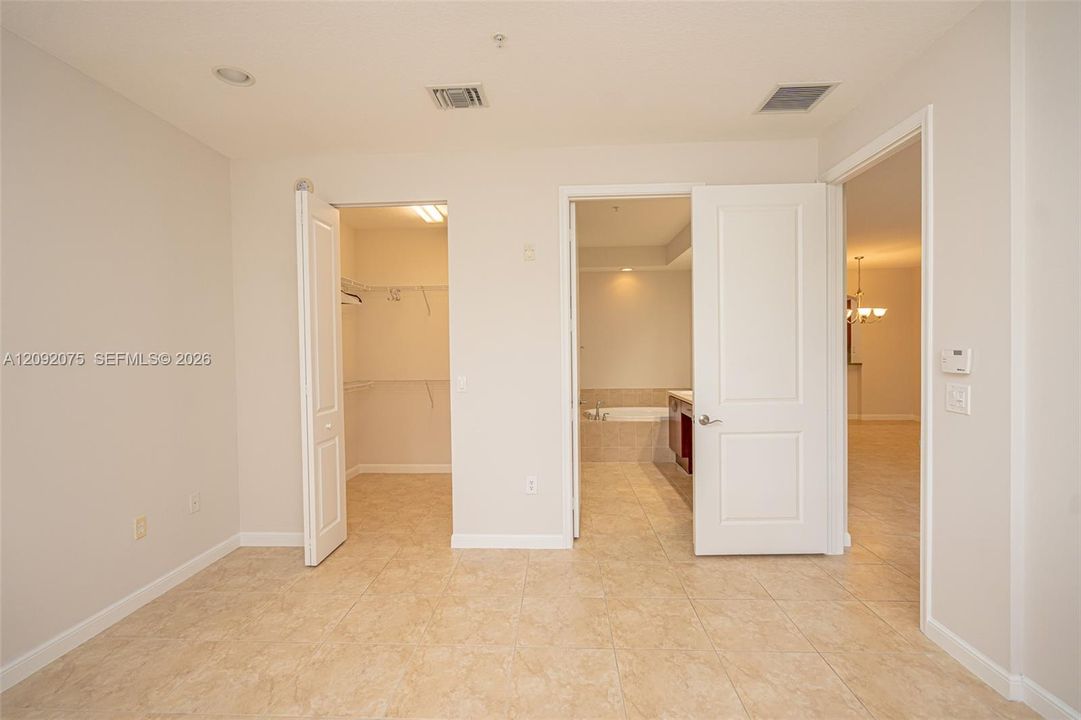 Tile flooring, recessed lighting, white interior doors, and a walk-in closet with built-in shelving