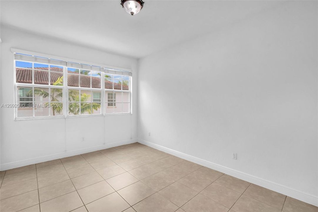 Interior room featuring neutral ceramic tile flooring, a multi-pane window with a grid pattern, and a flush-mount ceiling light fixture