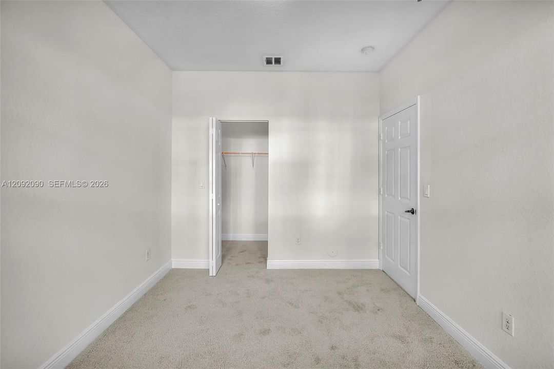 Neutral wall-to-wall carpeting, high ceilings, six-panel interior door, and walk-in closet with built-in shelving
