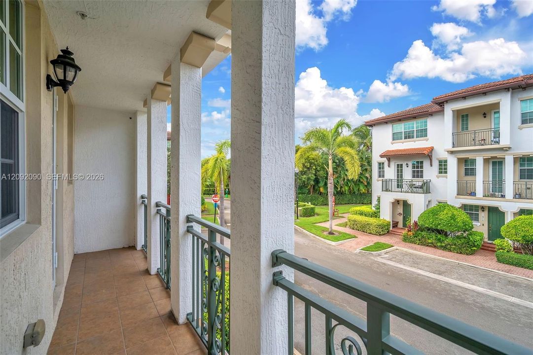 Covered balcony featuring tile flooring, structural columns, and a decorative metal railing