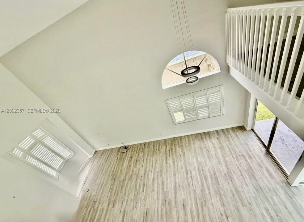 VIRTUAL STAGED -  Living and Dining room area looking down from the upstairs - notice bay window in the front and Bahama Shutters on both windows.