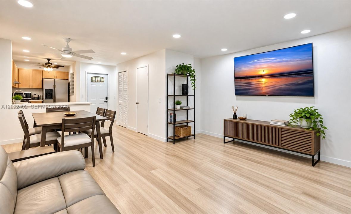 TV console & plants virtually staged for illustrative purposes. Open-concept interior featuring wood-finish flooring, recessed lighting, and a breakfast bar