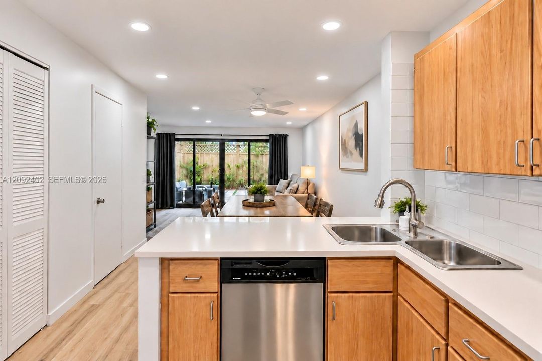 Kitchen featuring wood cabinetry, white countertops, a stainless steel dishwasher, an undermount double-basin sink with a gooseneck faucet, and white subway tile backsplash