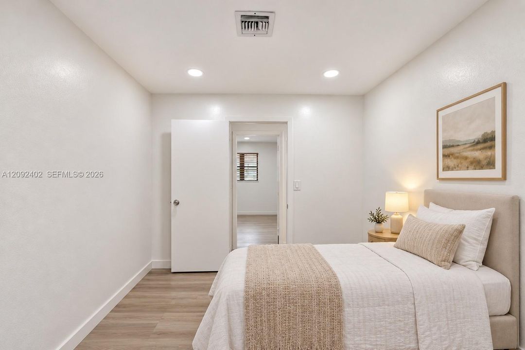 TV console & plants virtually staged for illustrative purposes.  Neutral-toned walls, wood-finish flooring, recessed lighting, and a crisp white interior door