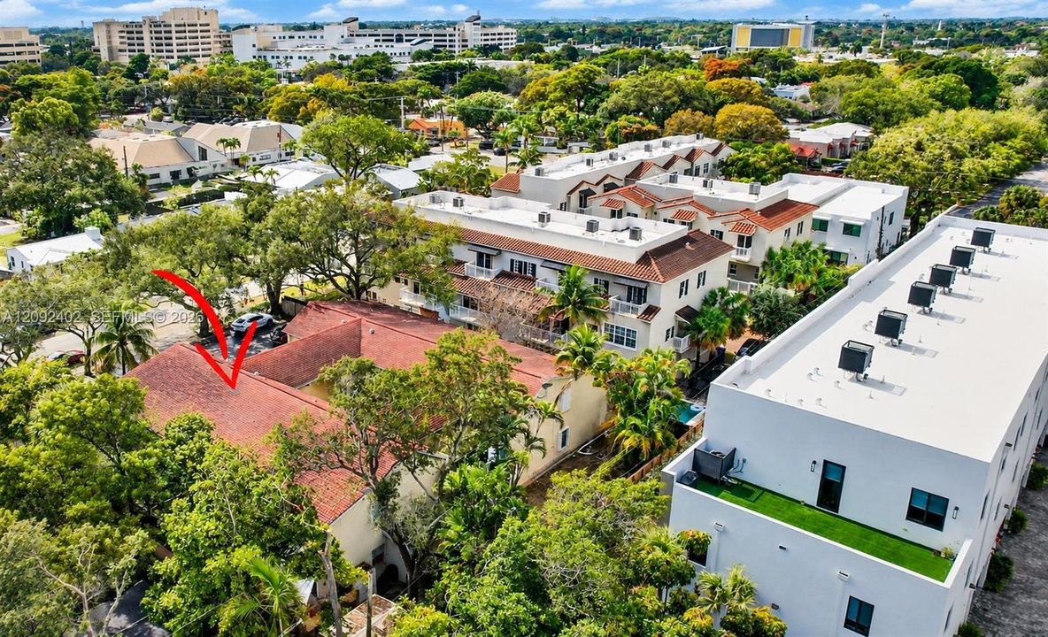 Aerial perspective featuring a multi-unit property with a multi-gabled terracotta tile roof, stucco exterior, and mature tree canopy landscaping