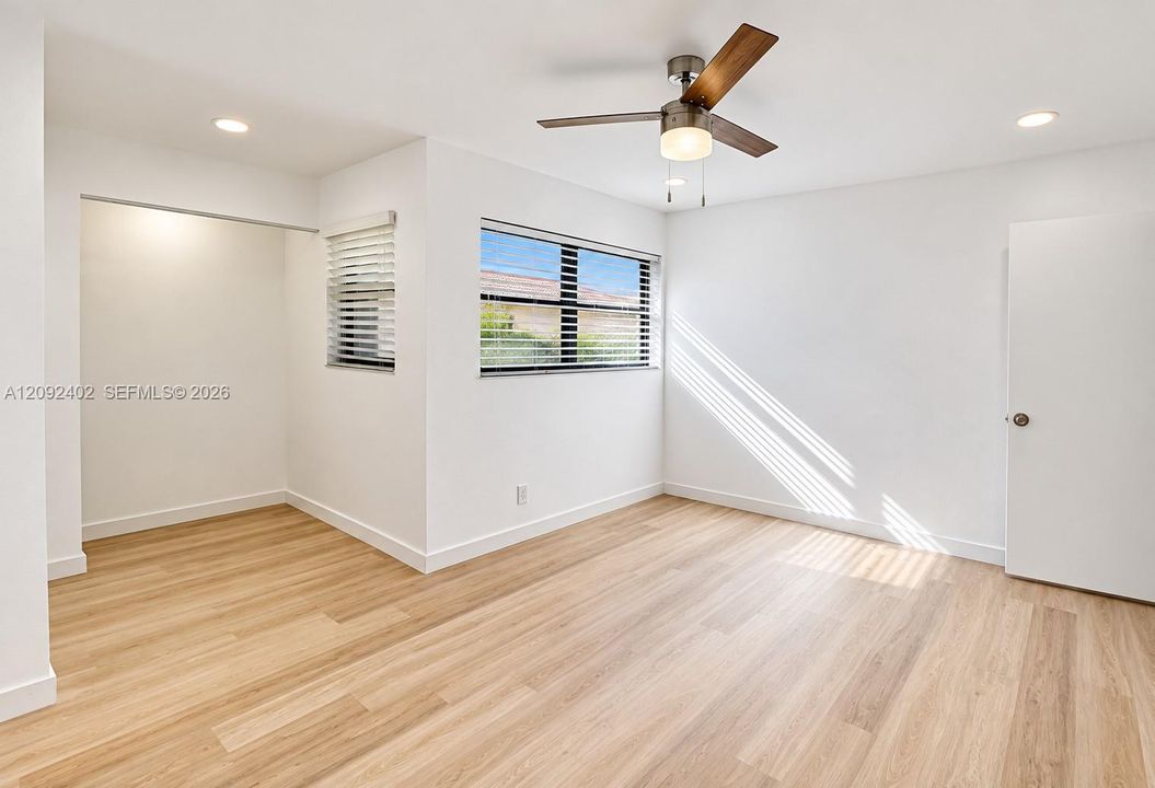 Neutral interior featuring wood-finish flooring, recessed lighting, a modern ceiling fan, and windows with integrated blinds
