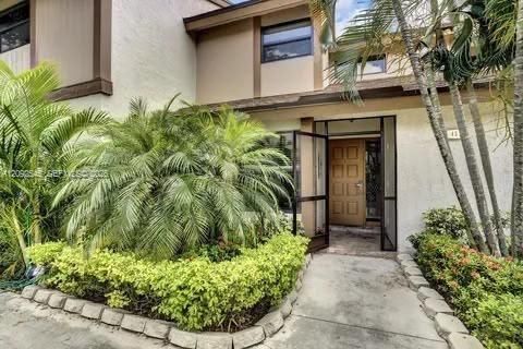 Front Entrance: Inviting covered front entryway flanked by well-manicured tropical plants and palm trees.