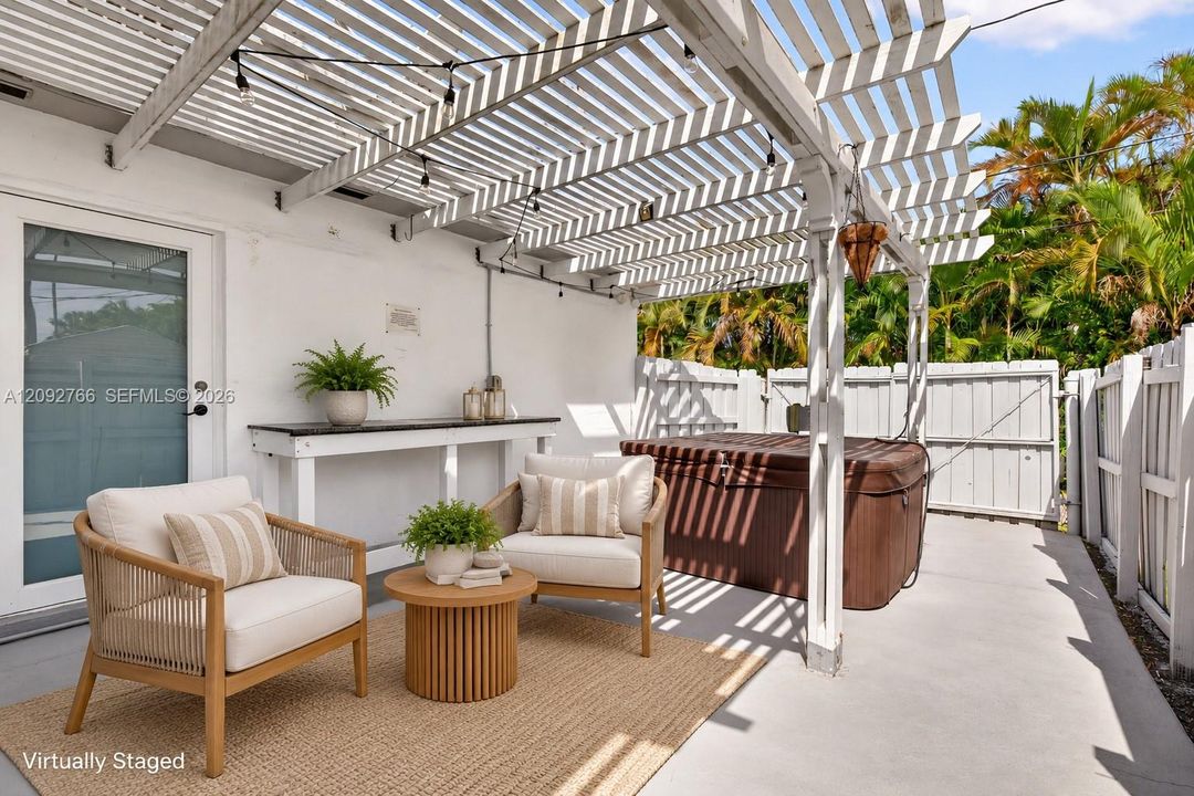 Outdoor patio featuring a white pergola, concrete flooring, built-in shelving, and a jetted spa