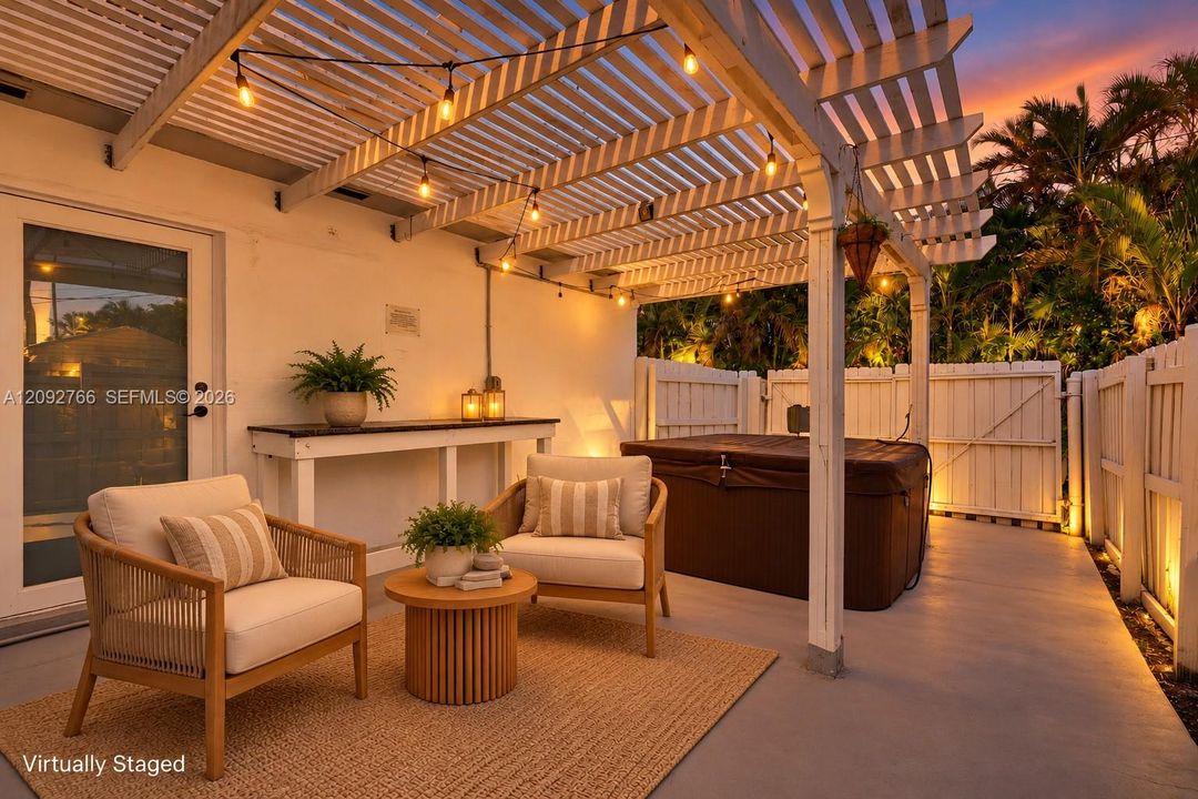 Covered patio area featuring a wooden pergola, concrete flooring, built-in wooden console table, and a private hot tub enclosed by perimeter fencing