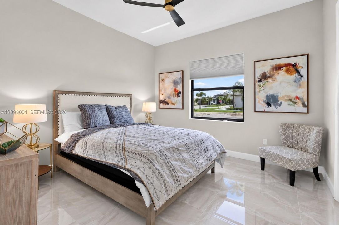 High ceilings featuring a matte black ceiling fan, neutral wall tones, large-format tile flooring, and a window with a roller shade