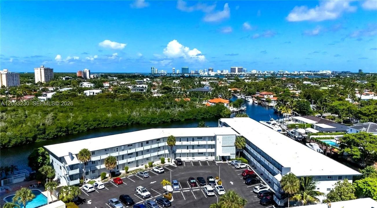 Low-rise residential building with balconies, surface parking, and an outdoor pool