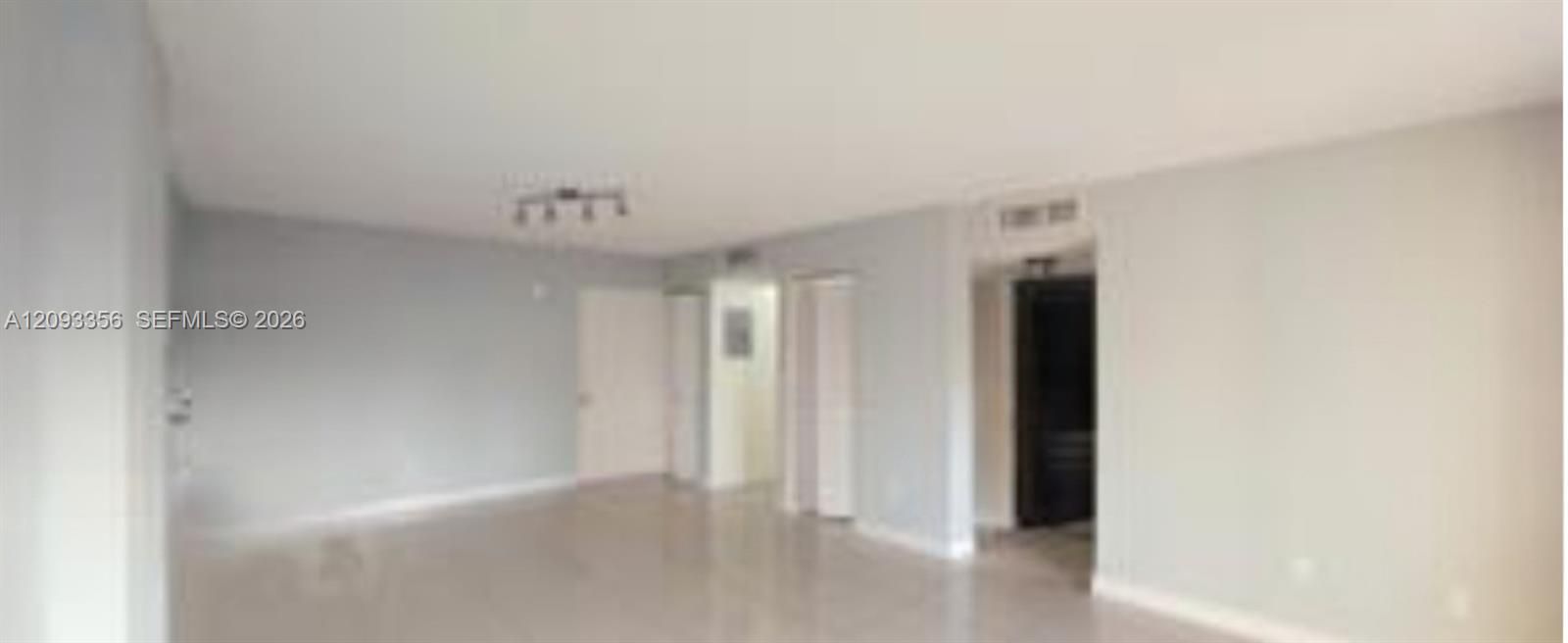 Open-concept living space featuring large-format tile flooring, sliding glass doors, and dual sets of bi-fold closet doors
