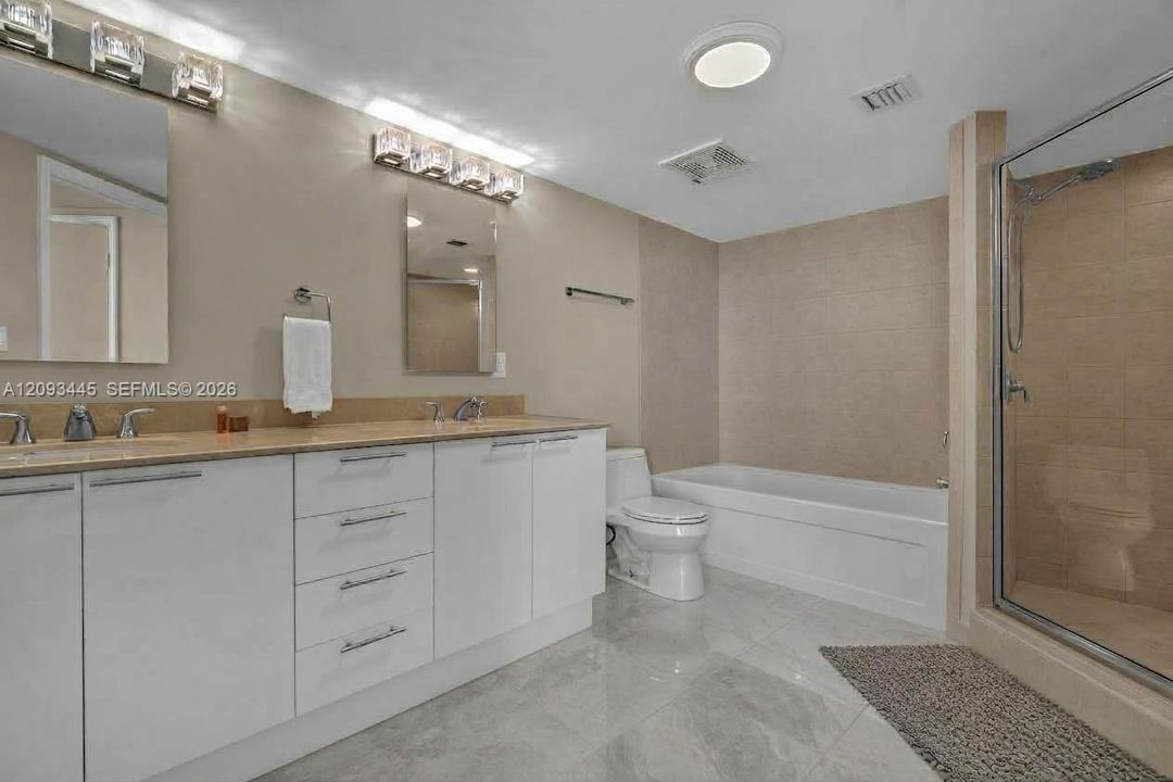Spa-inspired primary bathroom featuring a dual-sink vanity with ample storage, wood-finish countertops, and polished nickel fixtures