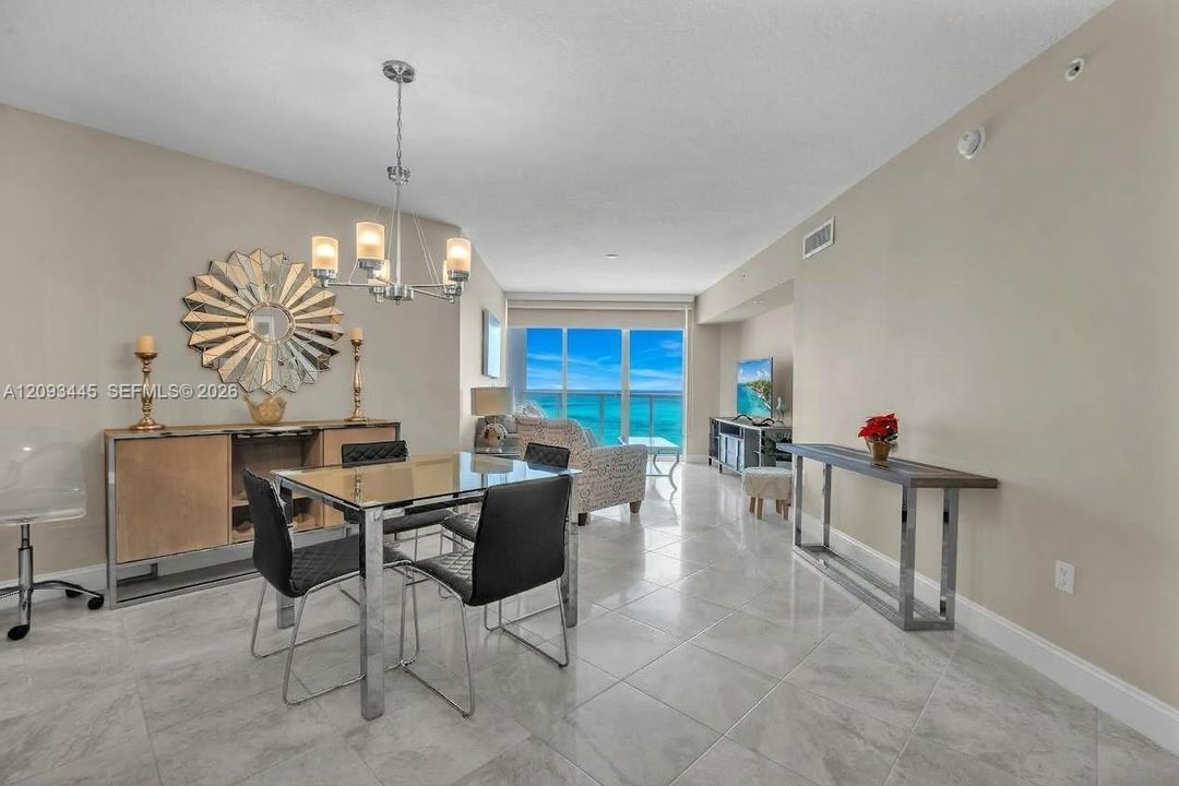 Spacious interior with tile flooring, a contemporary chandelier, and direct outdoor access through glass doors