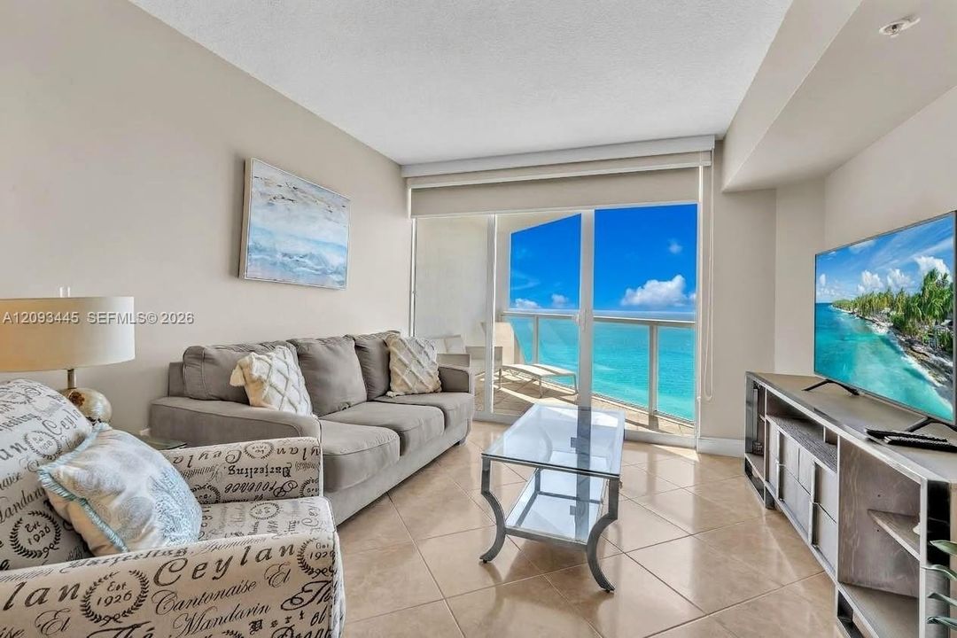 Sliding glass doors, balcony access, tile flooring, and neutral wall tones
