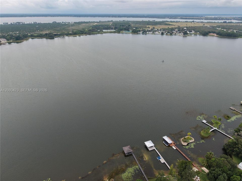 Aerial perspective of lakefront property featuring multiple boat docks, covered boat slips, and native vegetation