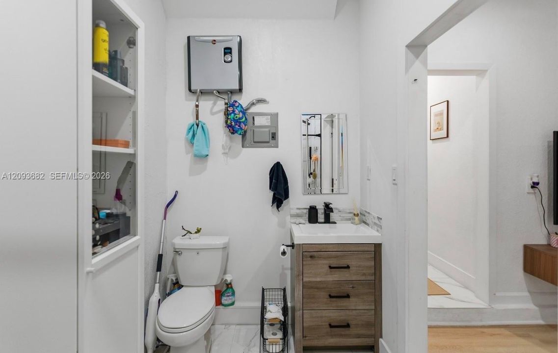 Built-in wall cabinetry, vanity with wood-finish cabinetry, matte black faucet, and stone-finish flooring