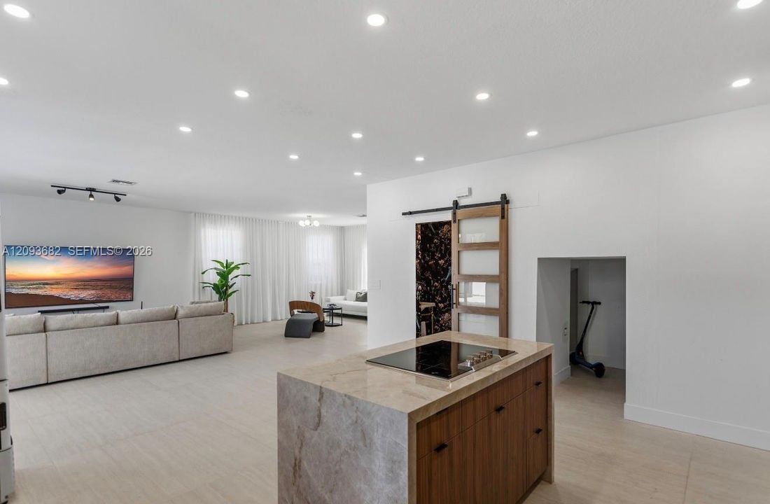 Center island featuring a stone-finish countertop, integrated cooktop, and wood-finish cabinetry