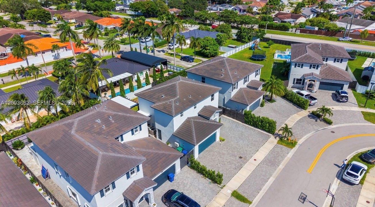 Aerial perspective featuring two-story residences with concrete tile roofing, multi-car garages, and paver driveways