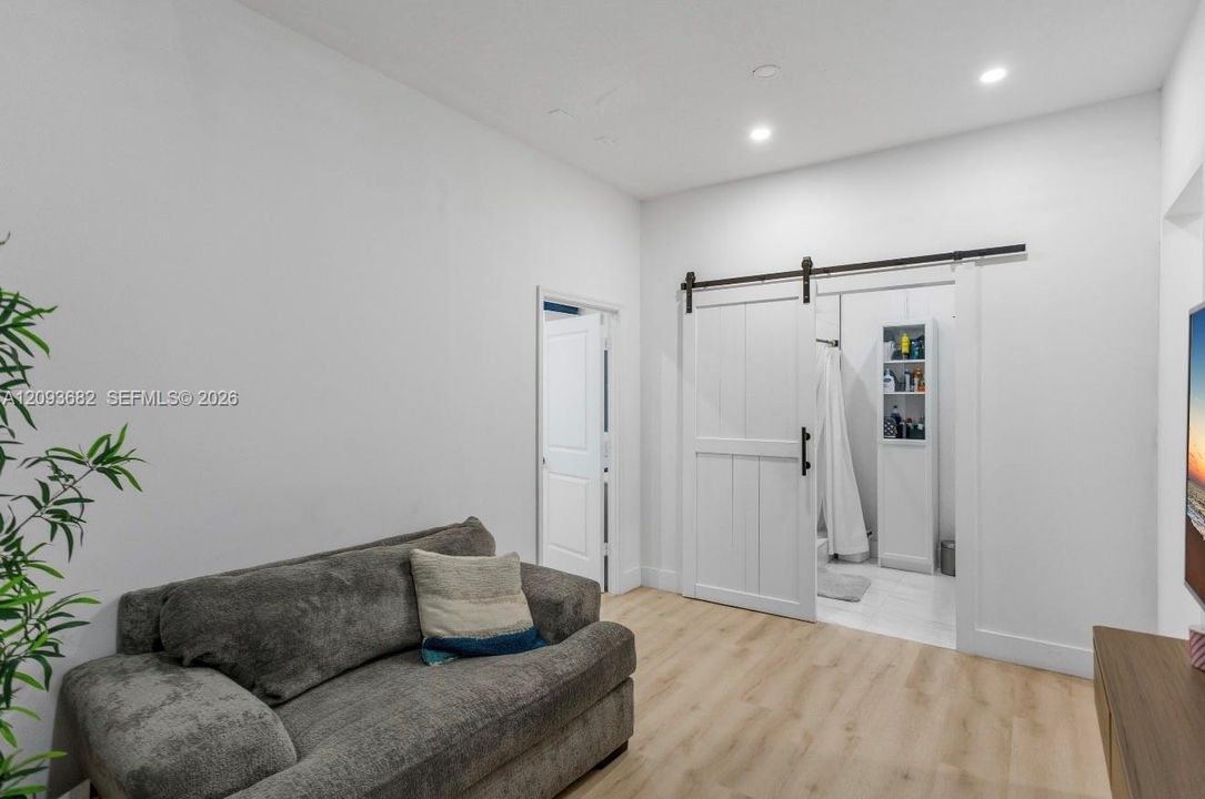 Interior space featuring wood-finish flooring, recessed lighting, and a white sliding barn-style door with black hardware