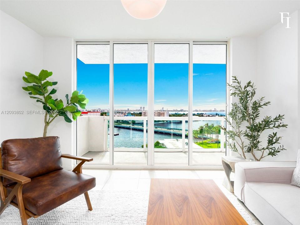 Floor-to-ceiling glass panel doors, white tiled flooring, and a glass-railed balcony featuring coastal water and cityscape scenery