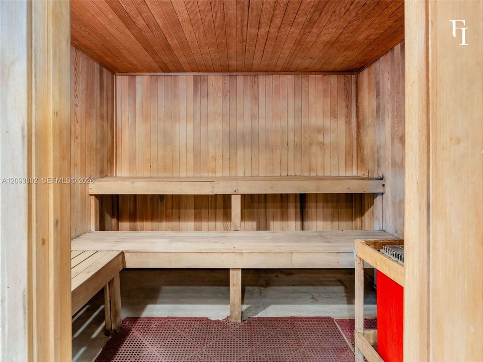 Sauna featuring tongue-and-groove wood paneling, multi-level built-in bench seating, and an integrated heating unit