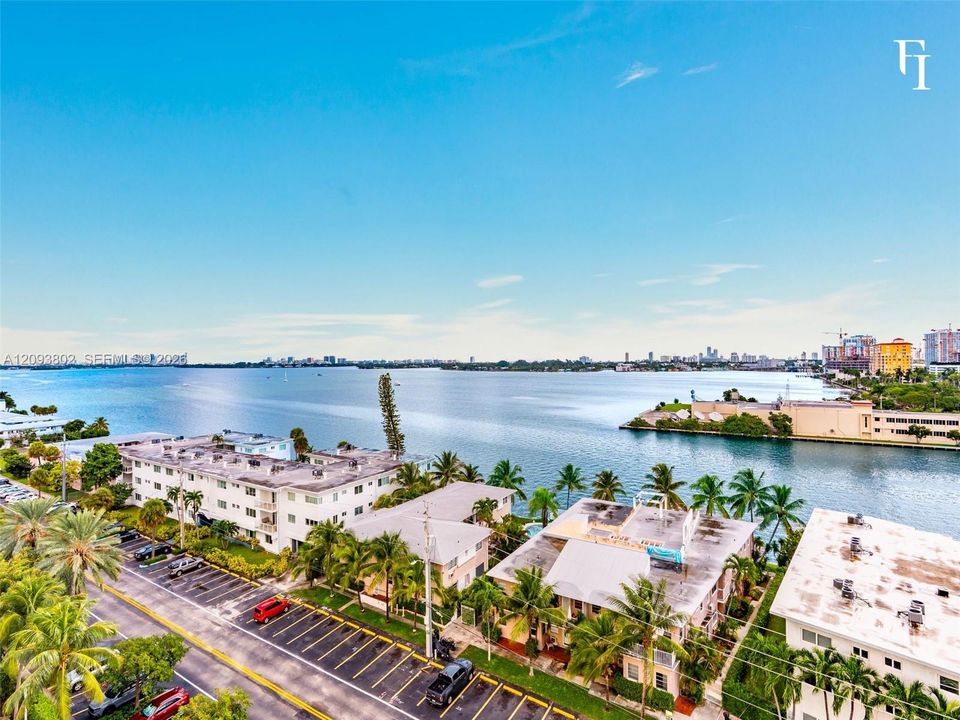 Aerial perspective featuring expansive coastal waterfront, mature palm trees, and established building exteriors