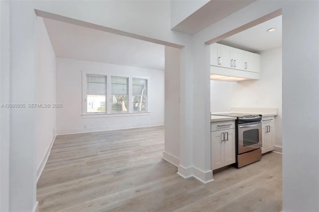 Wood-finish flooring throughout, white cabinetry with silver-tone hardware, and multiple windows with white trim