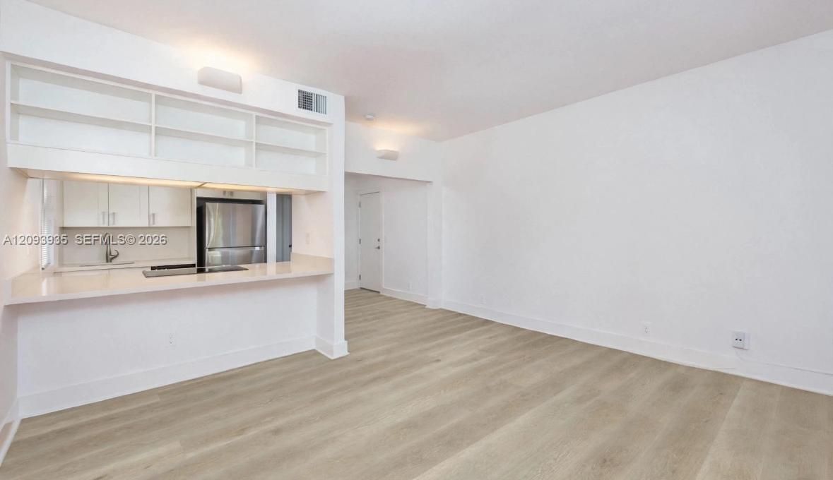 Kitchen area featuring white cabinetry, quartz-finish countertops, stainless steel appliances, and wood-finish flooring
