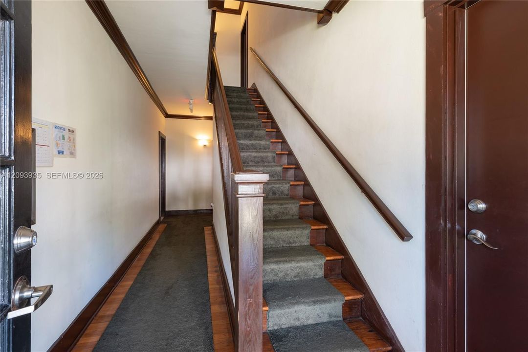 Entryway featuring dark-stained wood trim, wooden stairwell with a square newel post, and hardwood flooring