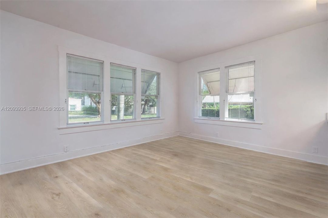 Interior space featuring wood-finish flooring, white walls, and multiple double-hung windows with white casing