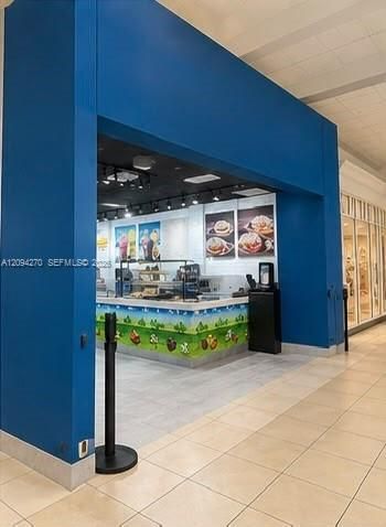 Commercial storefront featuring high-visibility blue architectural framing, recessed track lighting, and a service counter with integrated stone-finish top