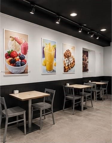 Black ceiling with adjustable track lighting, two-tone wall treatment, and neutral tile flooring