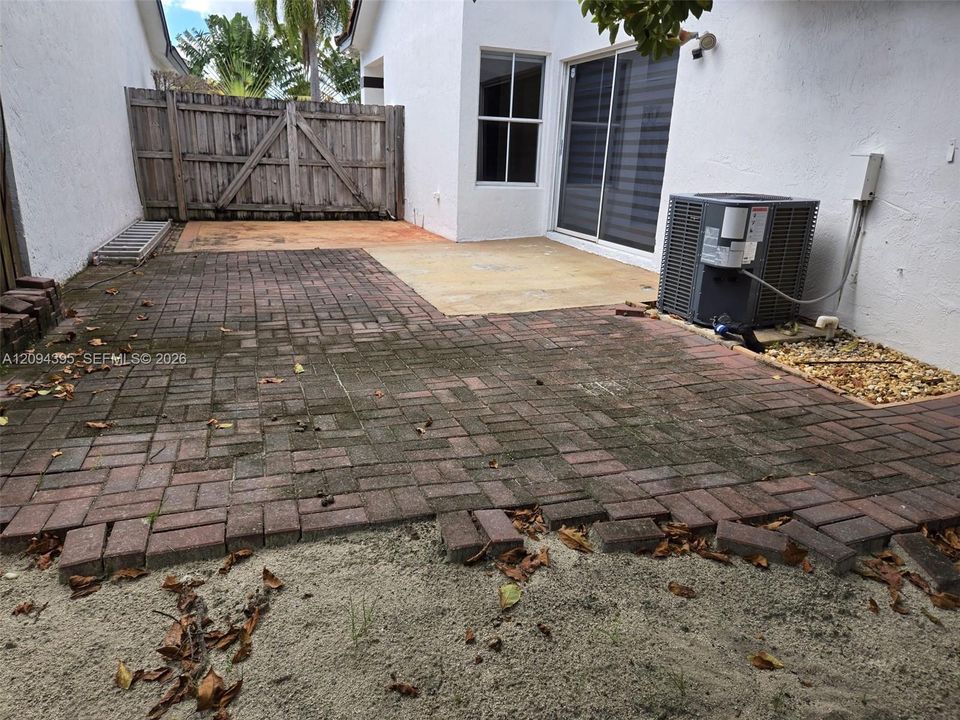 Exterior space featuring a brick-paver patio, concrete slab foundation, and a wood privacy fence