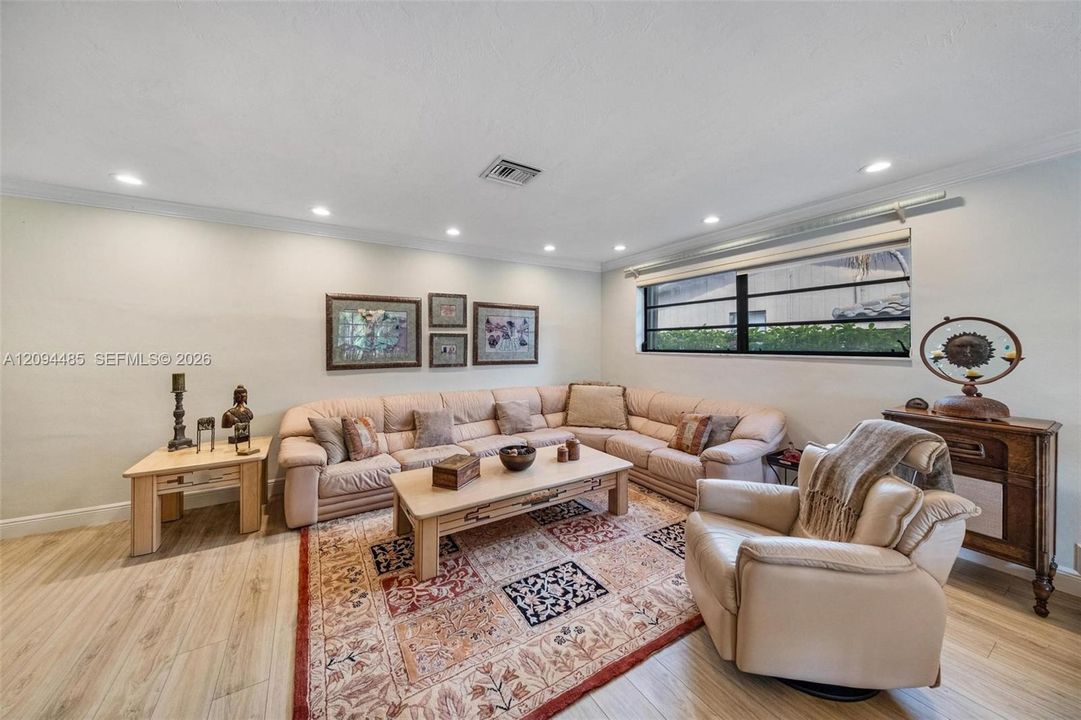 Living area featuring wood-finish flooring, recessed lighting, and a large horizontal window with black-framed horizontal muntins
