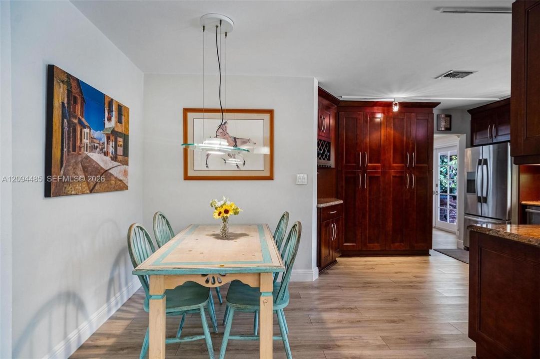 Custom floor-to-ceiling cabinetry with integrated wine storage, wood-finish flooring, and a multi-pendant glass light fixture