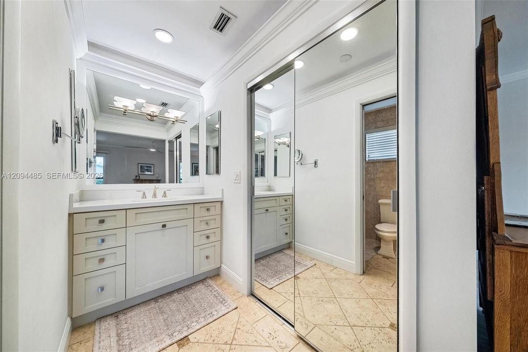 Vanity featuring a stone-surface countertop, integrated undermount sink, multi-drawer cabinetry, and a large wall-mounted mirror