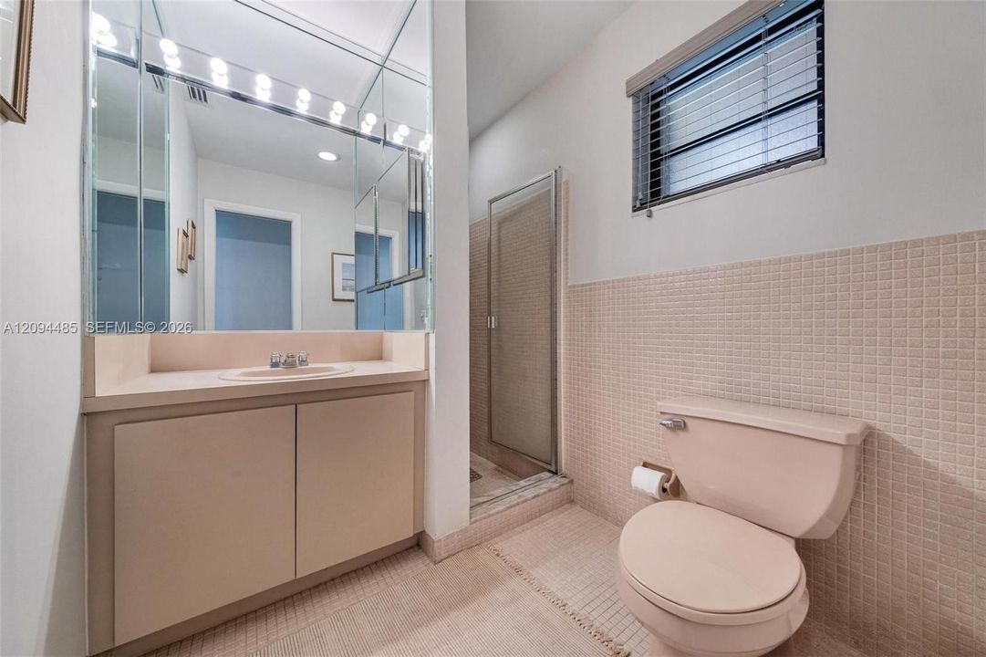 Bathroom featuring a vanity with an integrated basin, a floor-to-ceiling mirror, a separate shower enclosure, and neutral-toned wall tiling