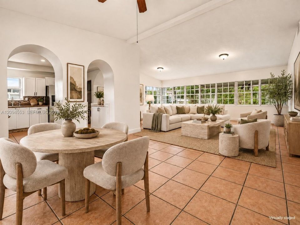 Virtually staged: living and dining area with arched entry to the kitchen