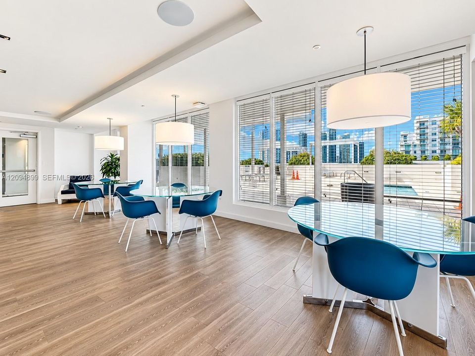 Expansive common area featuring wood-finish flooring, floor-to-ceiling windows, and drum-style pendant lighting