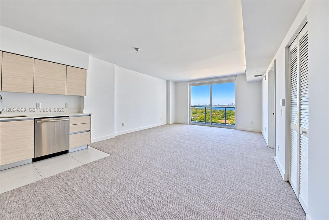 Light-toned cabinetry, stainless steel dishwasher, carpeting, floor-to-ceiling glass door, and exterior balcony