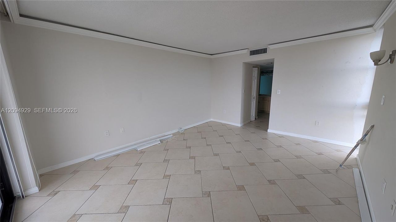 Interior space featuring diamond-pattern tile flooring with inlay detailing, crown molding, and neutral wall paint