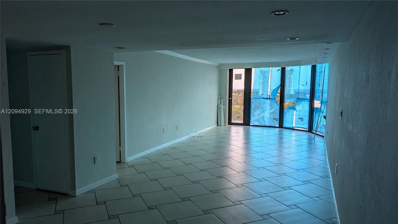 Open-concept interior featuring large-format diagonal tile flooring, recessed lighting, and floor-to-ceiling windows